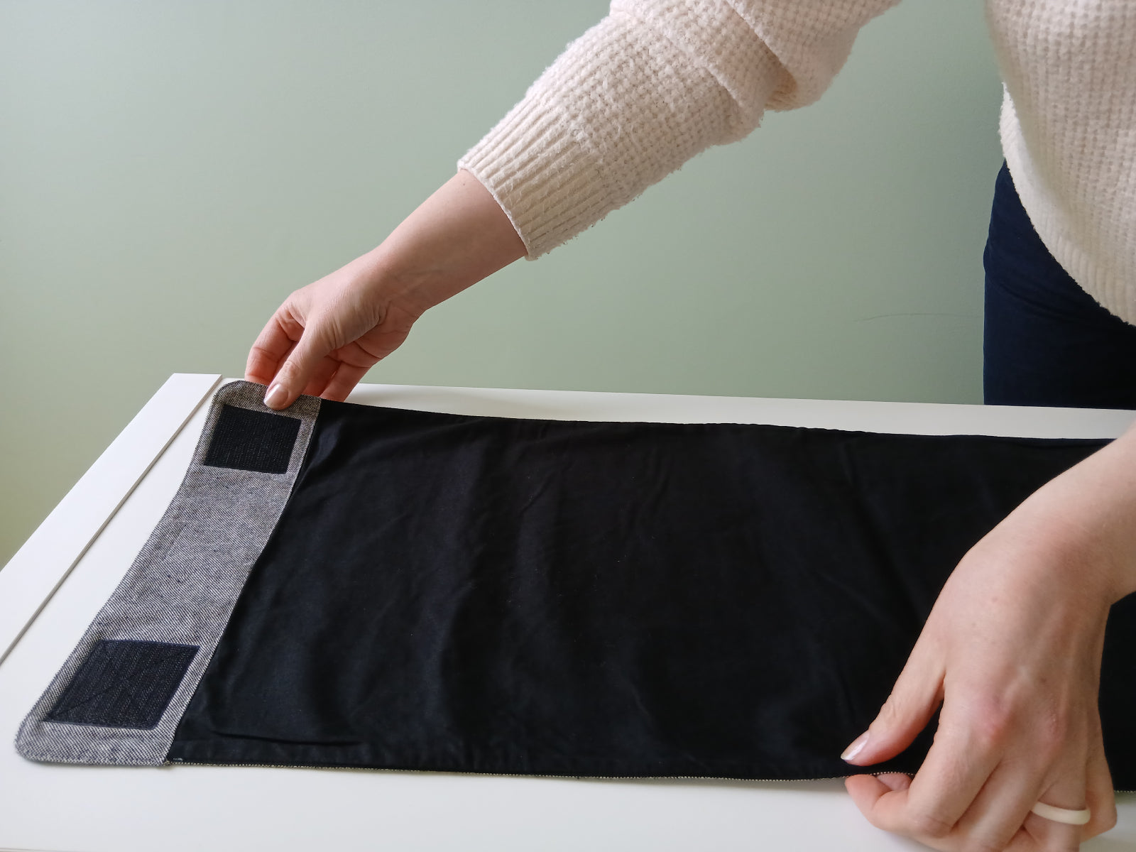 Hands place the Furl packing roll flat with the two square Velcro patches facing up, ready for packing.